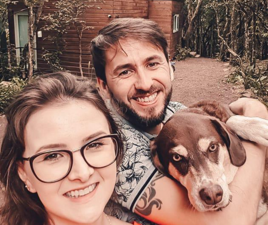 Um homem e uma mulher posam para uma foto com seu cachorro.