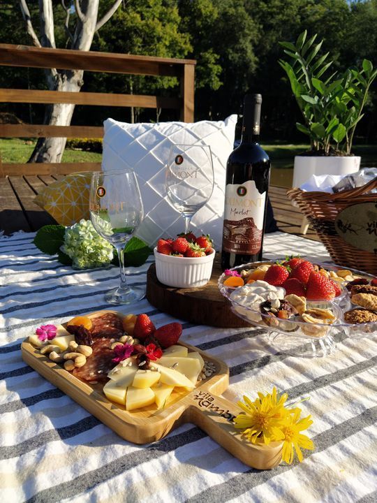 Uma mesa de piquenique com uma garrafa de vinho e uma bandeja de comida