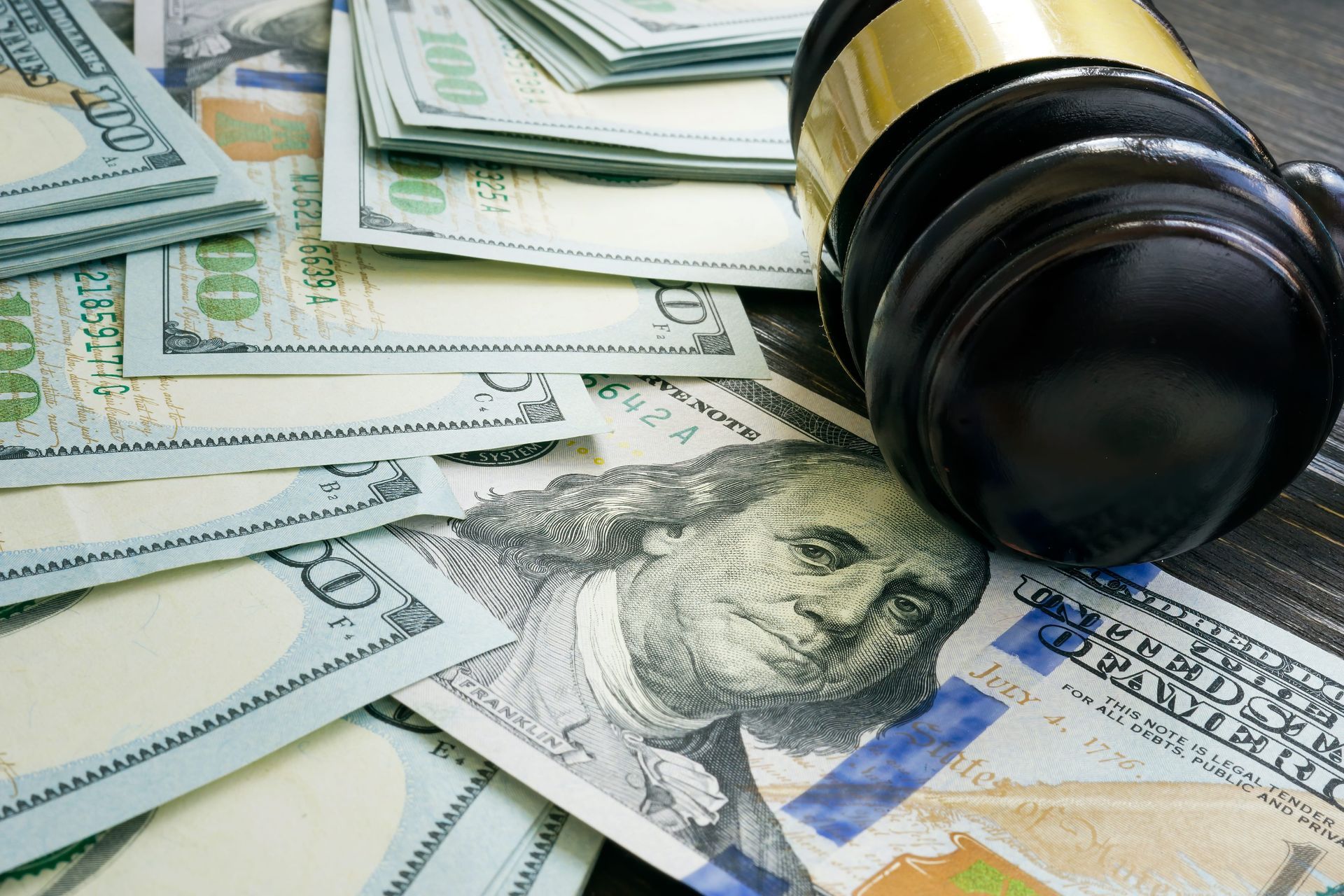 Gavel on U.S. dollar bills with a stack of cash, suggesting legal or financial enforcement