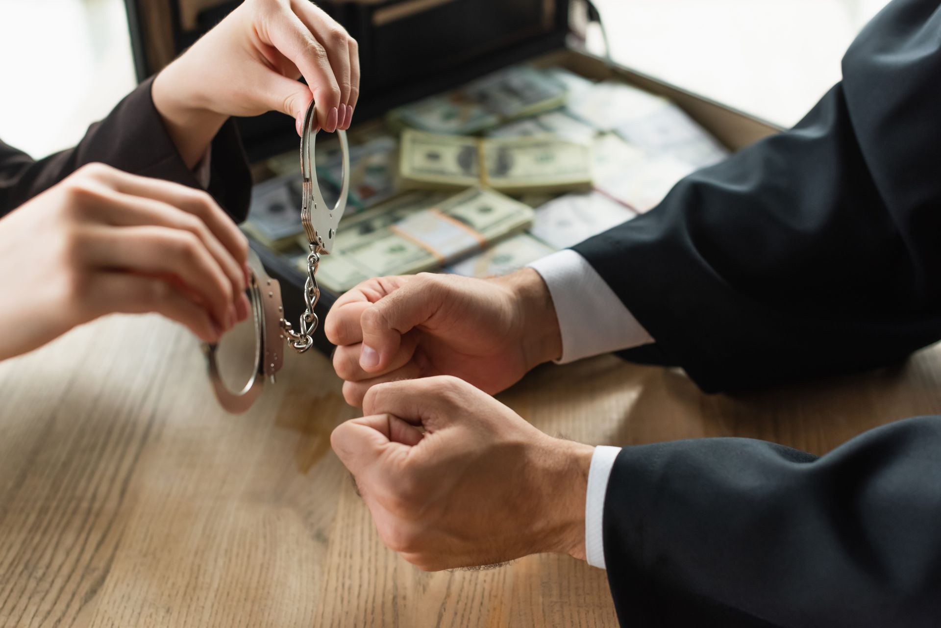 Hands exchanging a rosary over a table with scattered U.S. dollar bills