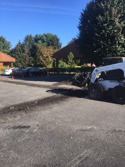 Damaged white car at curb beside a building, with debris and skid marks on the pavement