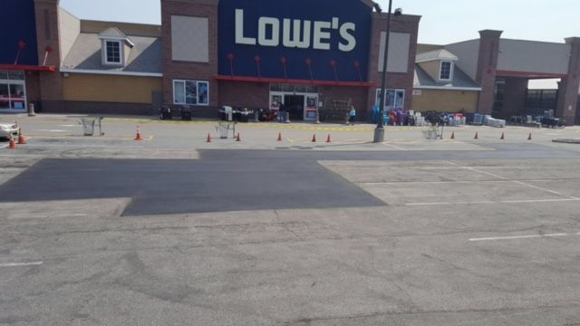 Lowe’s storefront and parking lot with scattered shopping carts under a clear sky