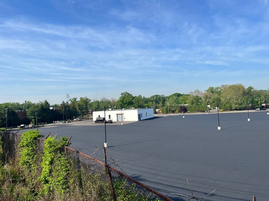 Flat commercial rooftop with white HVAC units under a blue sky, trees in the background.