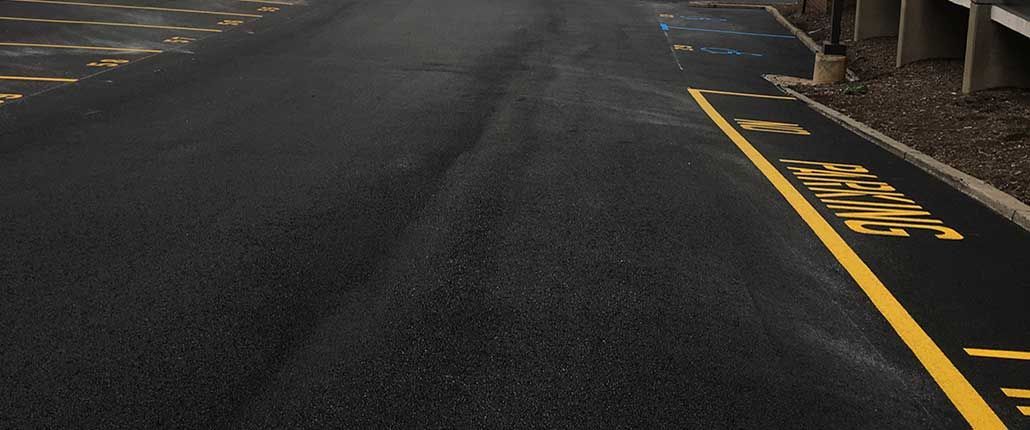 Curving asphalt road with yellow curb markings and a caution sign on the right side