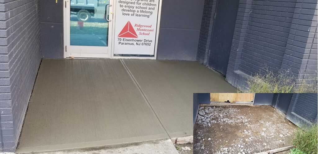 Accessible entrance ramp to a building with handrails and a door ahead, concrete walkway, and a notice sign.