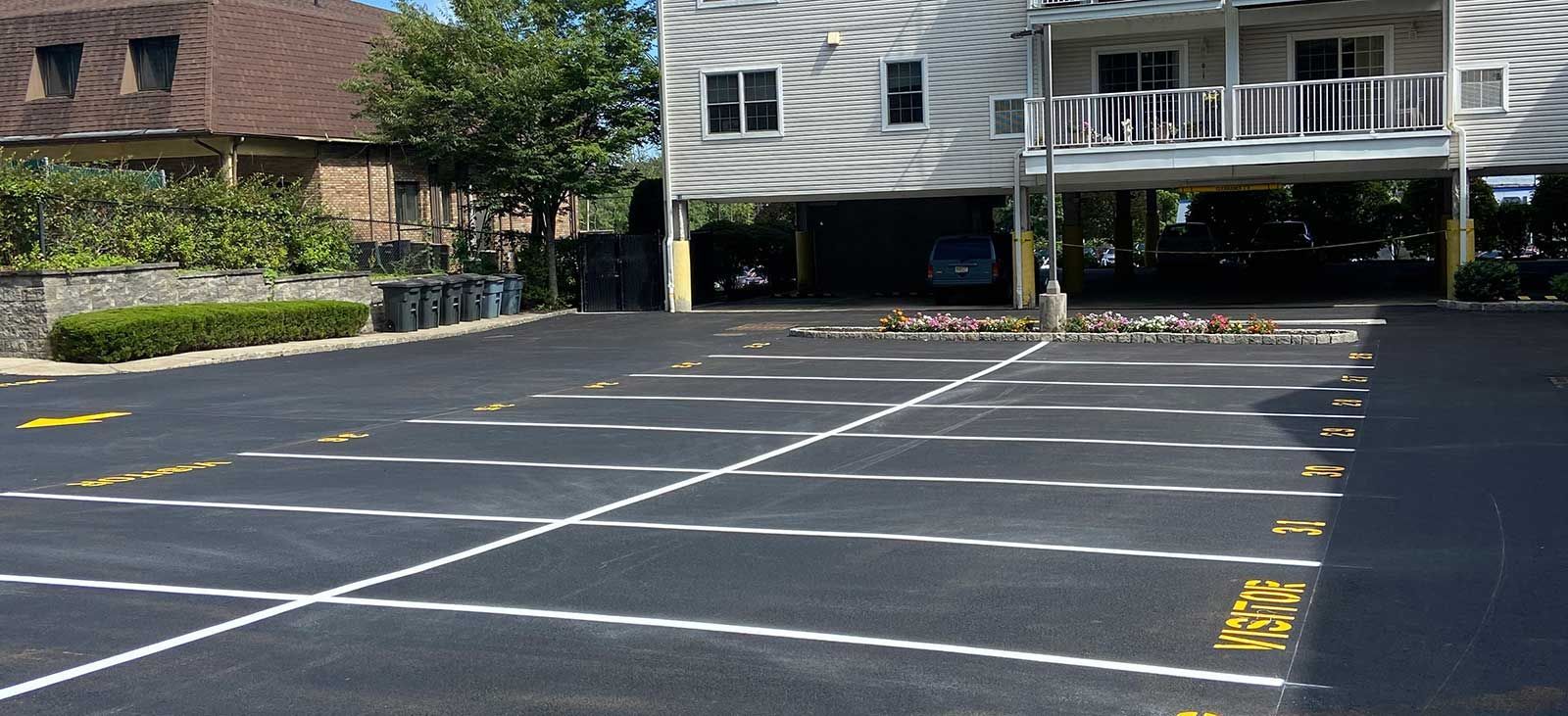Empty parking lot with painted spaces in front of a building and trees