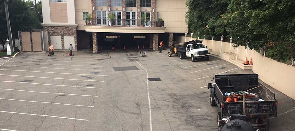 Empty parking lot beside a building, with a white SUV and a black truck near the far end.