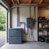 Een grijswaterboiler met opslagunit in een garage. Metalen leidingen en draden bevestigd aan de muur.
