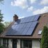 Zonnepanelen geïnstalleerd op een woonhuisdak onder een gedeeltelijk bewolkte hemel.