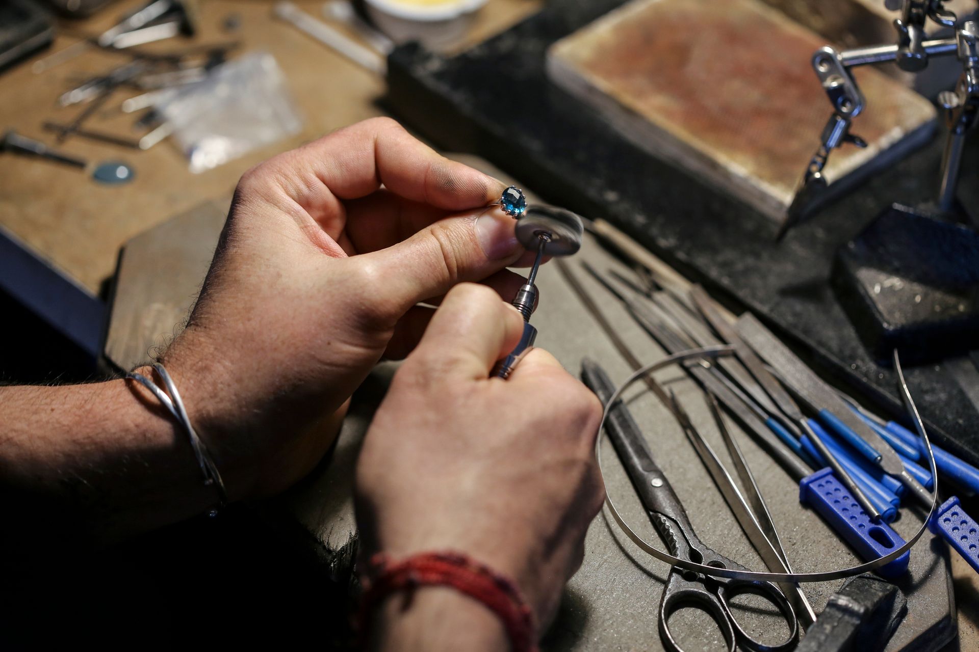 Una persona sta lavorando a un gioiello seduto a un tavolo.