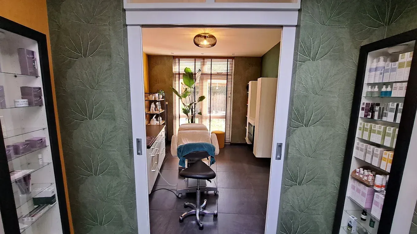Een kappersstoel staat in een smalle deuropening, tegenover een zonovergoten kamer met planken aan beide zijden.