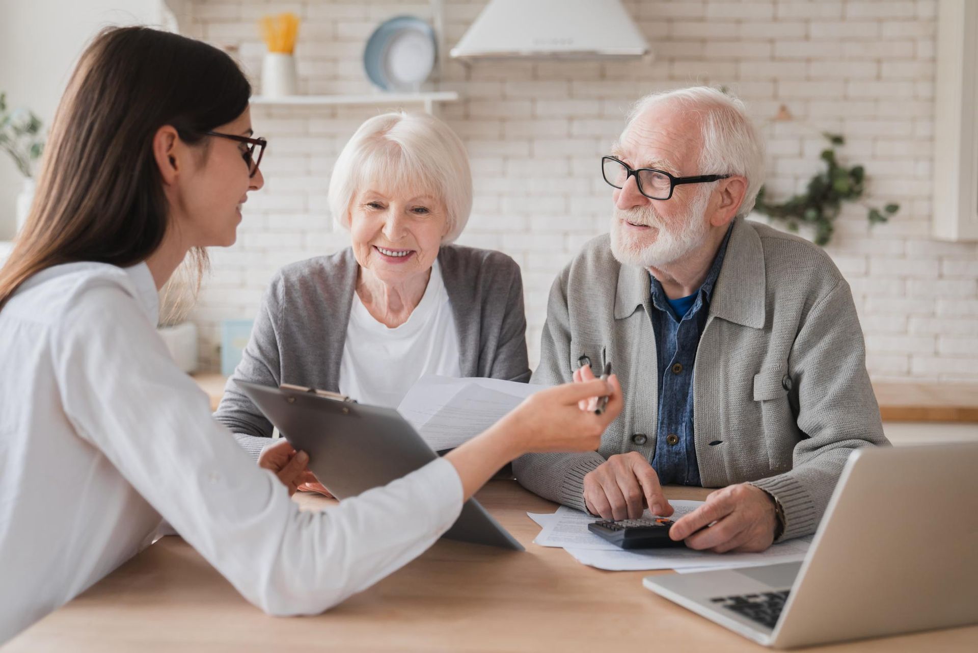 Financial advisor reviewing documents with smiling elderly couple at a table.