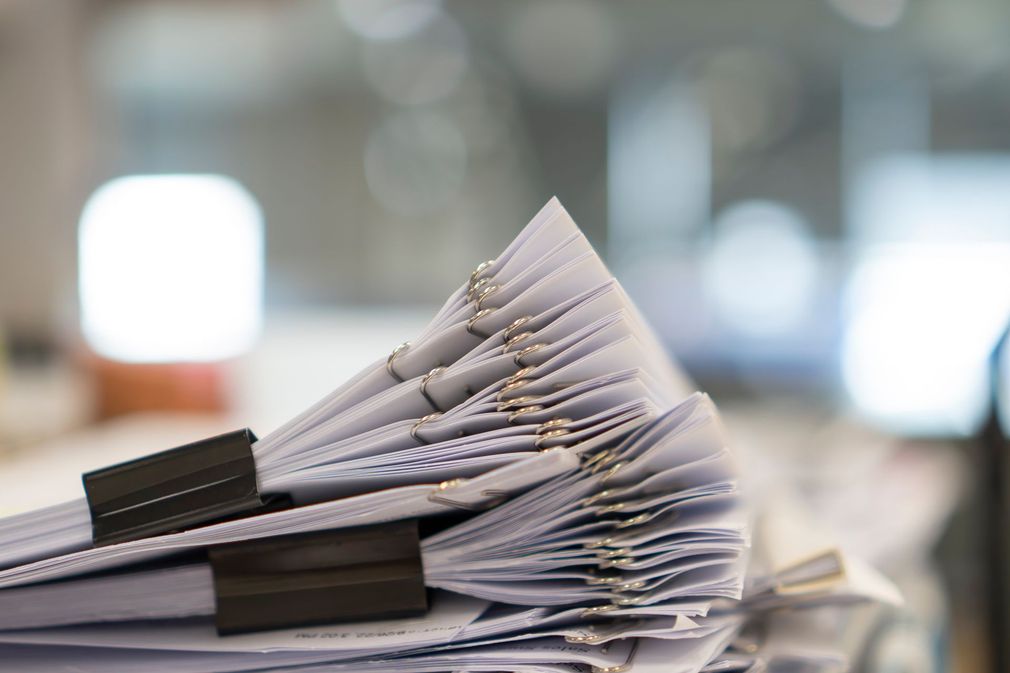 Person pointing at document while meeting at a table. Coffee cup and calculator nearby.