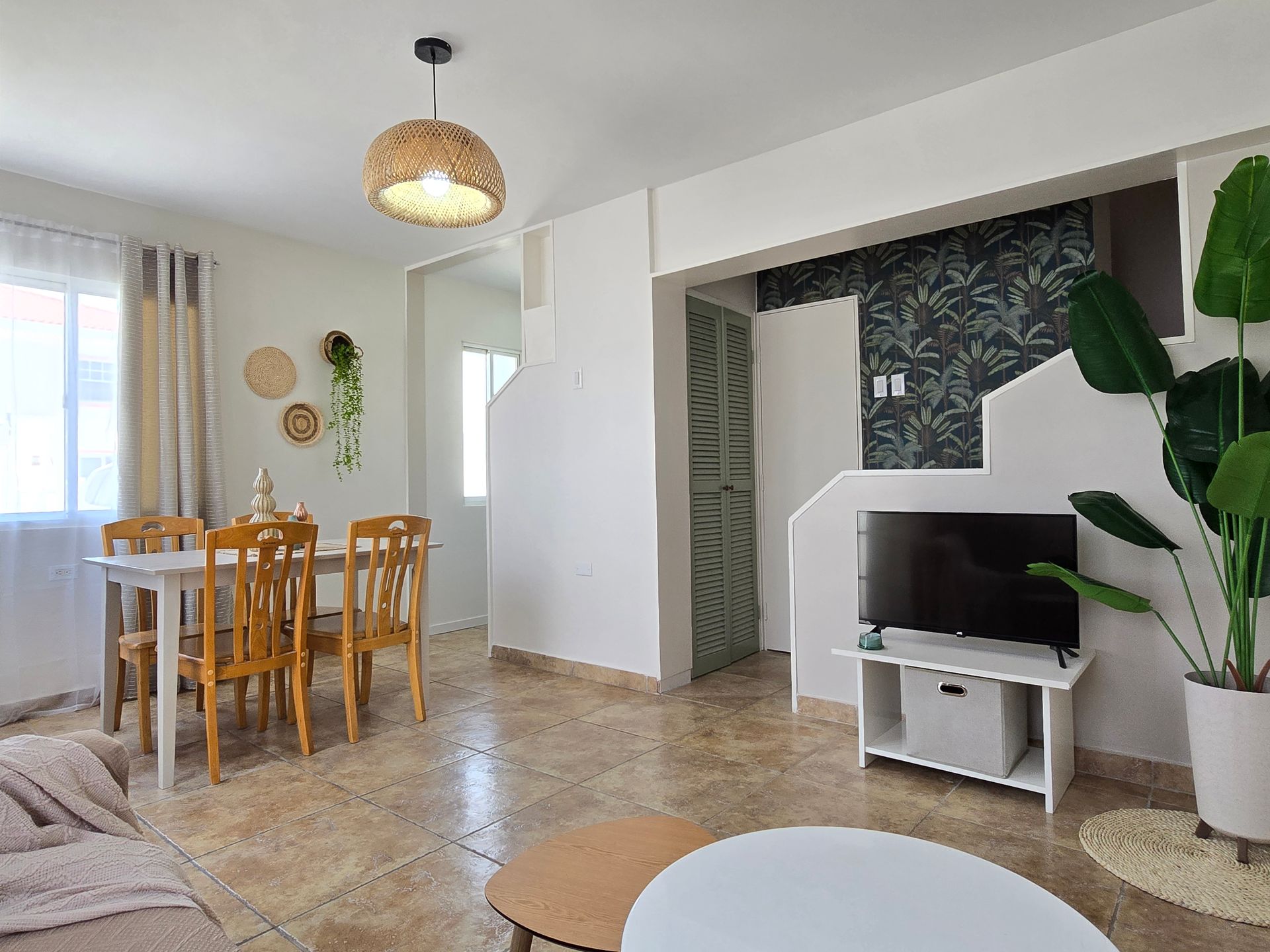A living room with a table , chairs , a couch and a refrigerator.