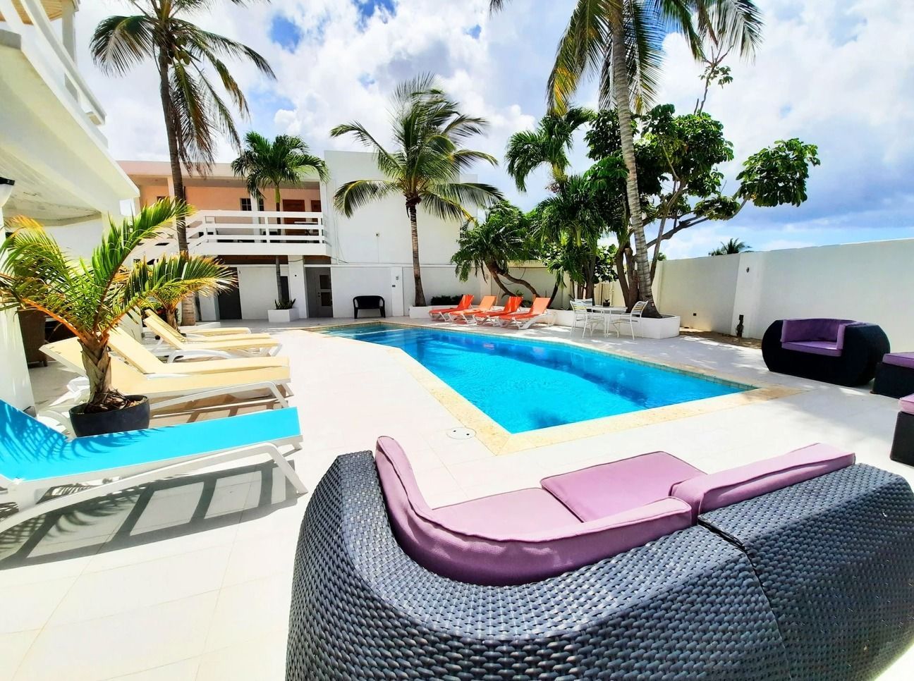 A swimming pool surrounded by chairs and palm trees