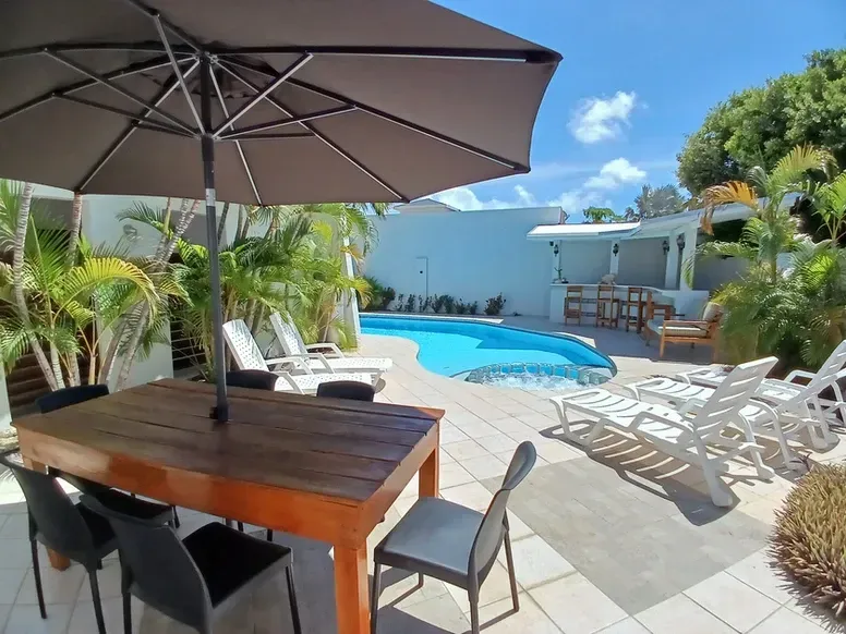 A table and chairs under an umbrella next to a swimming pool