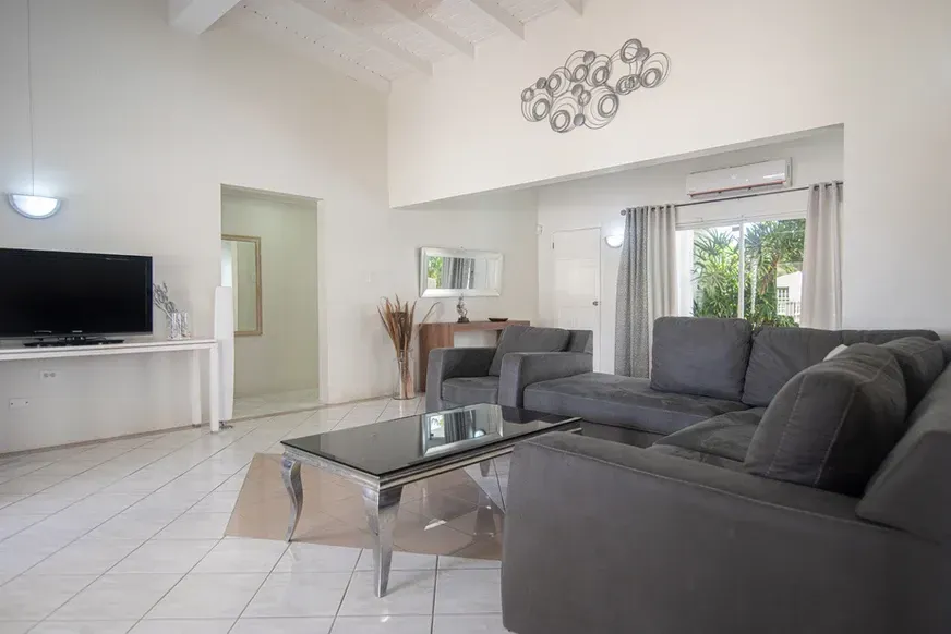 A living room with a couch , chair , coffee table and television.