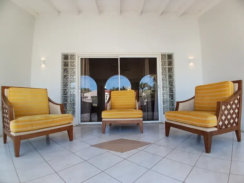 A patio with yellow chairs and a sliding glass door