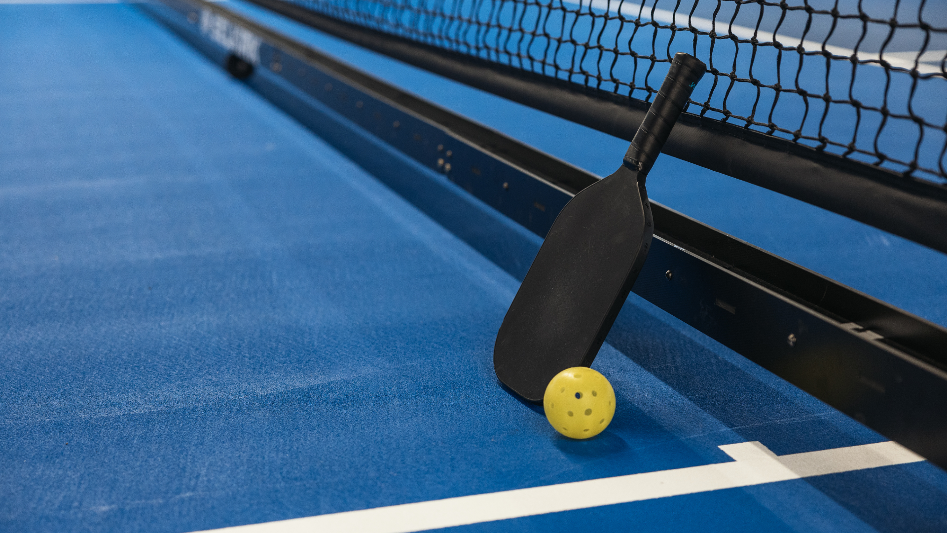A paddle and ball on a blue tennis court