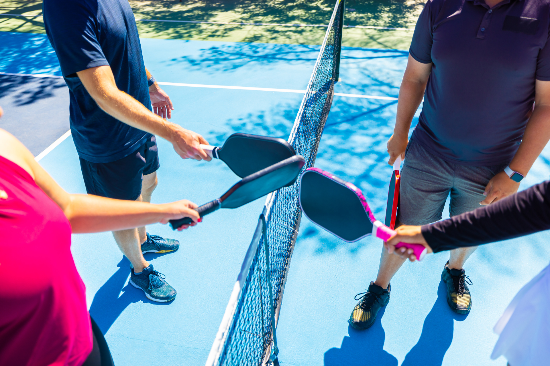 A group of people are playing pickleball on a tennis court.