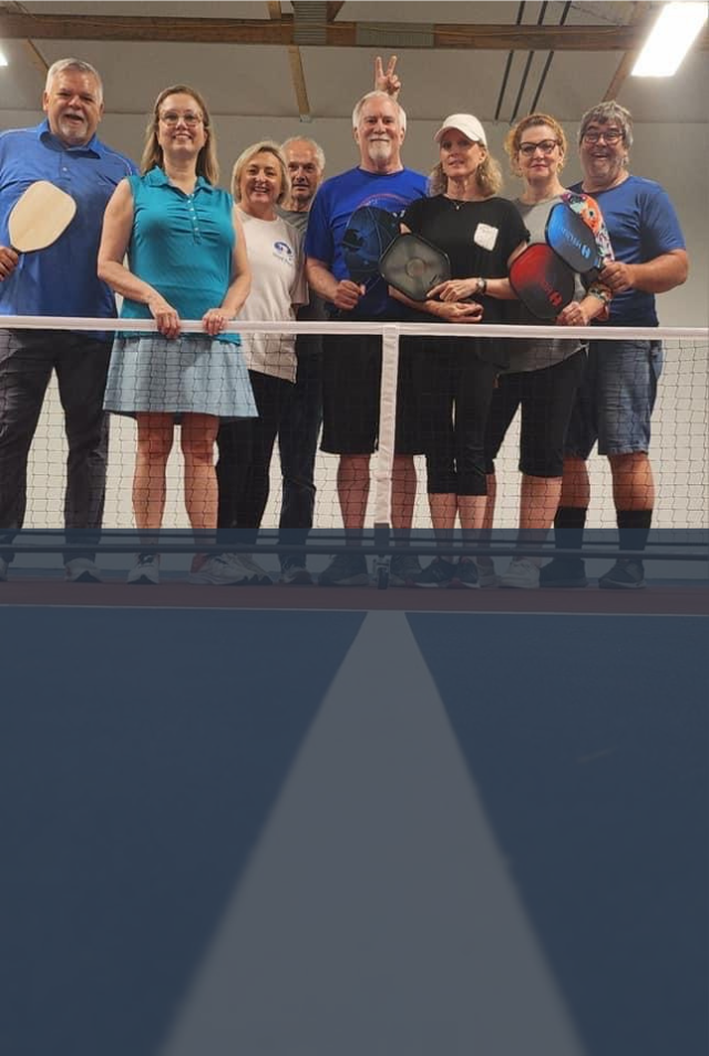 a group of people standing on a balcony holding pickleball rackets including one that says ' a ' on it
