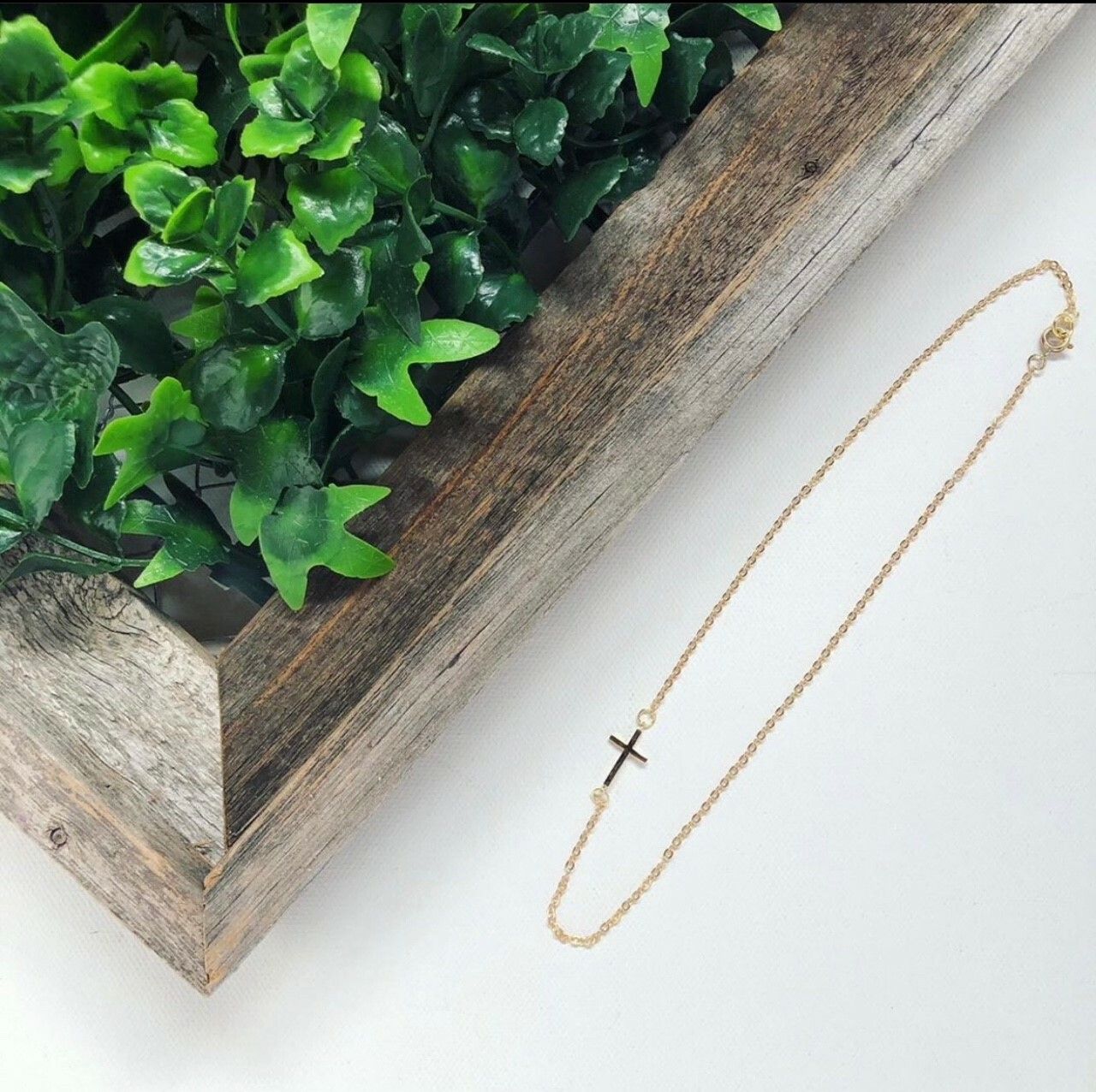 A necklace with a cross on it is in front of a wooden box