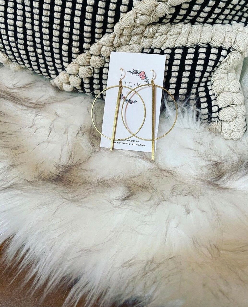 A pair of hoop earrings sitting on top of a fur rug.