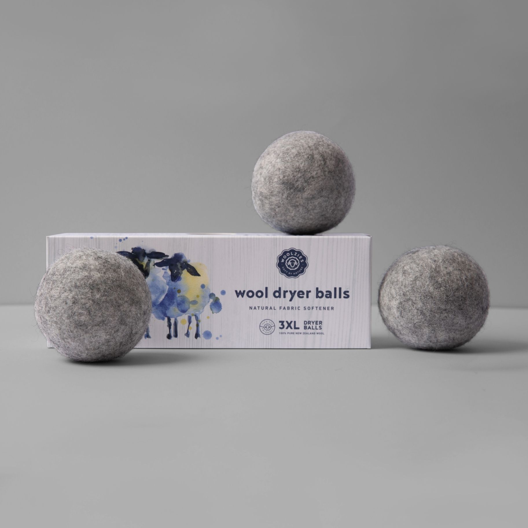 Three wool dryer balls are sitting on top of a box on a table.
