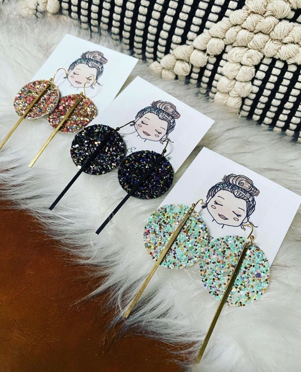 Three pairs of earrings are sitting on a furry surface.