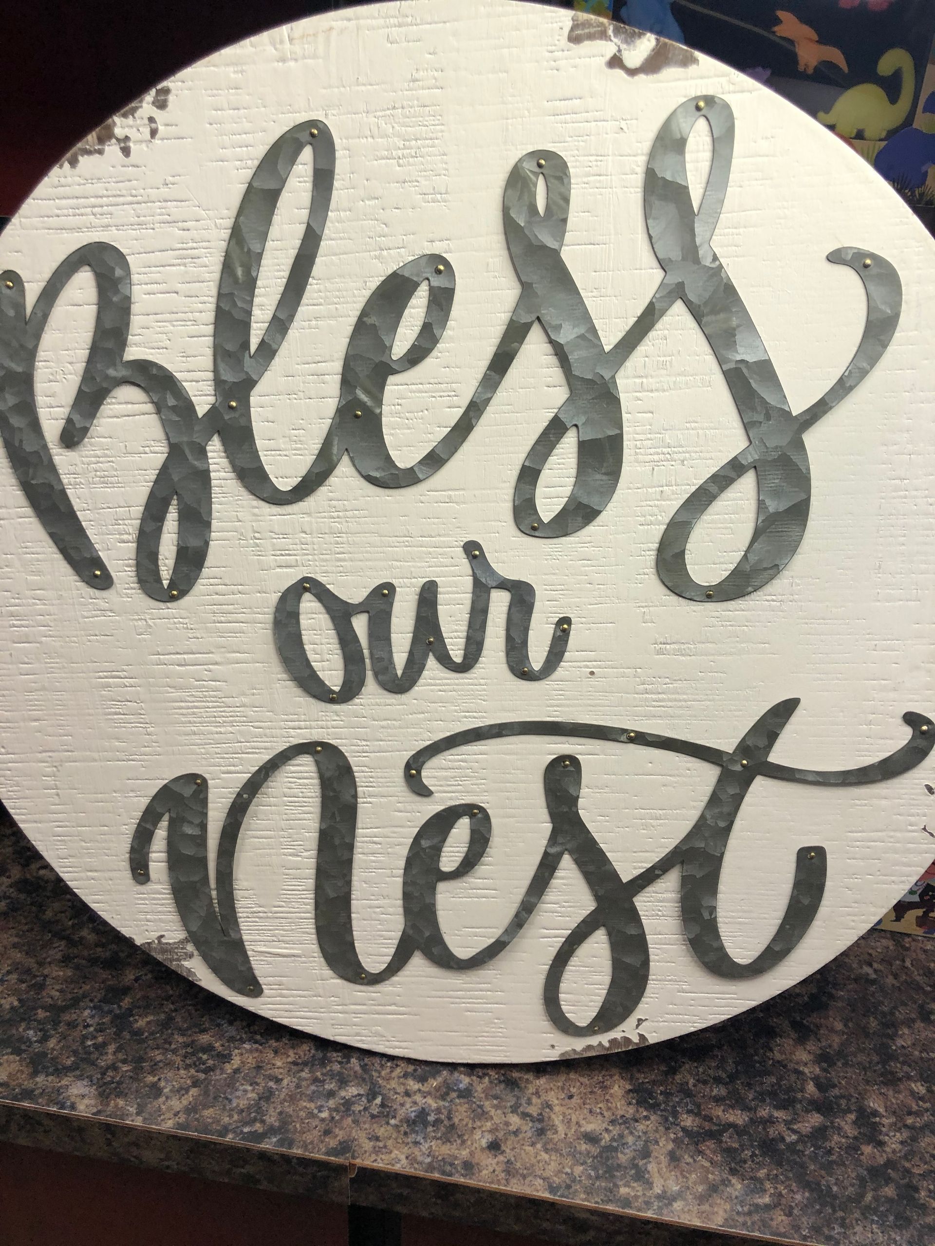 A wooden sign that says `` bless our nest '' is sitting on a table.