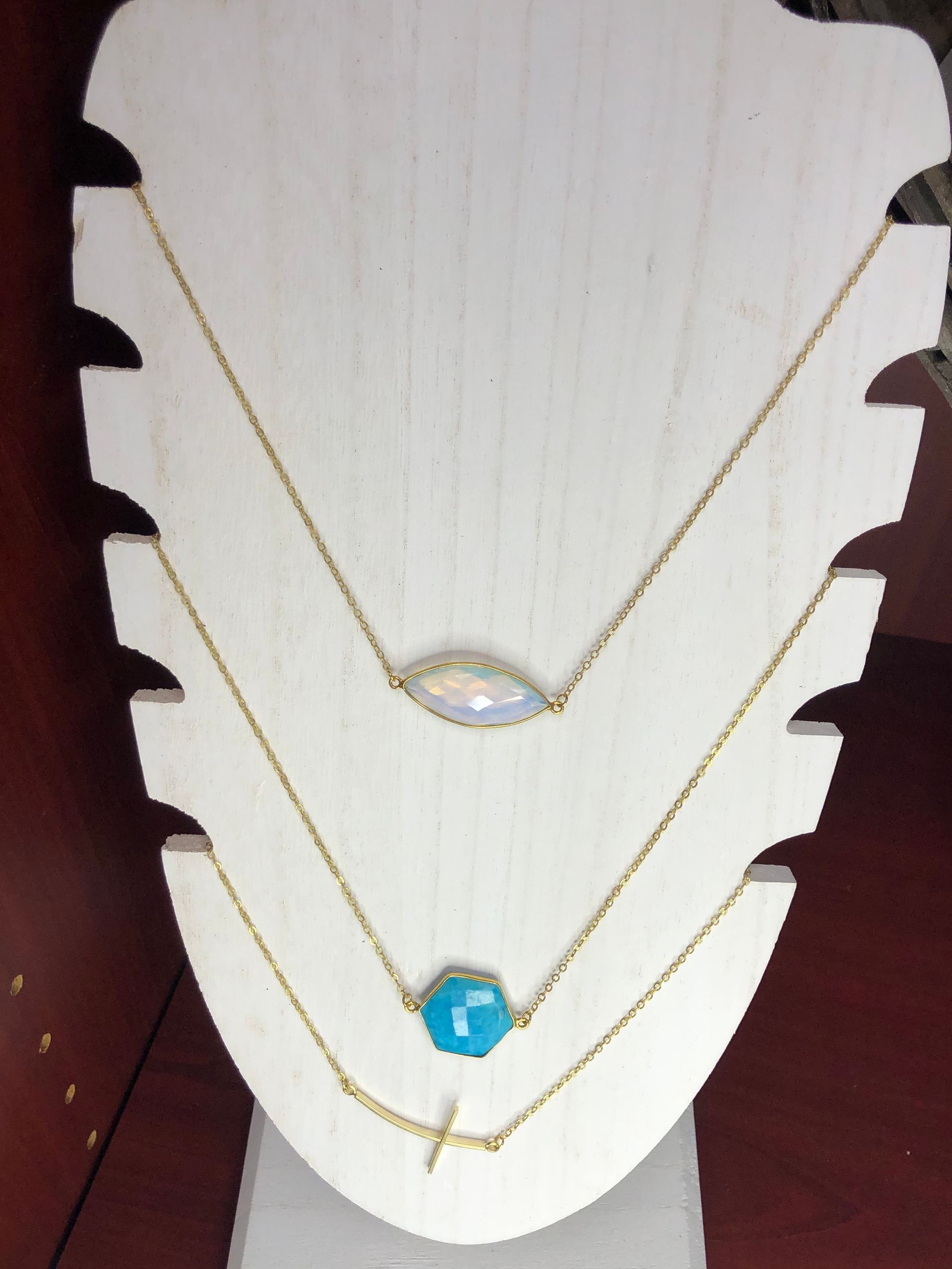 Three necklaces are displayed on a white mannequin