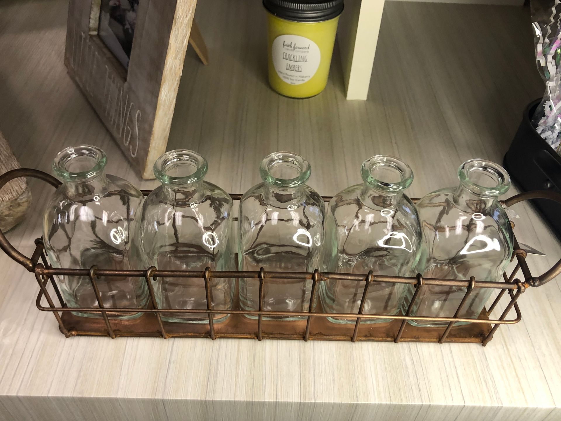A row of glass bottles in a wire basket on a table.
