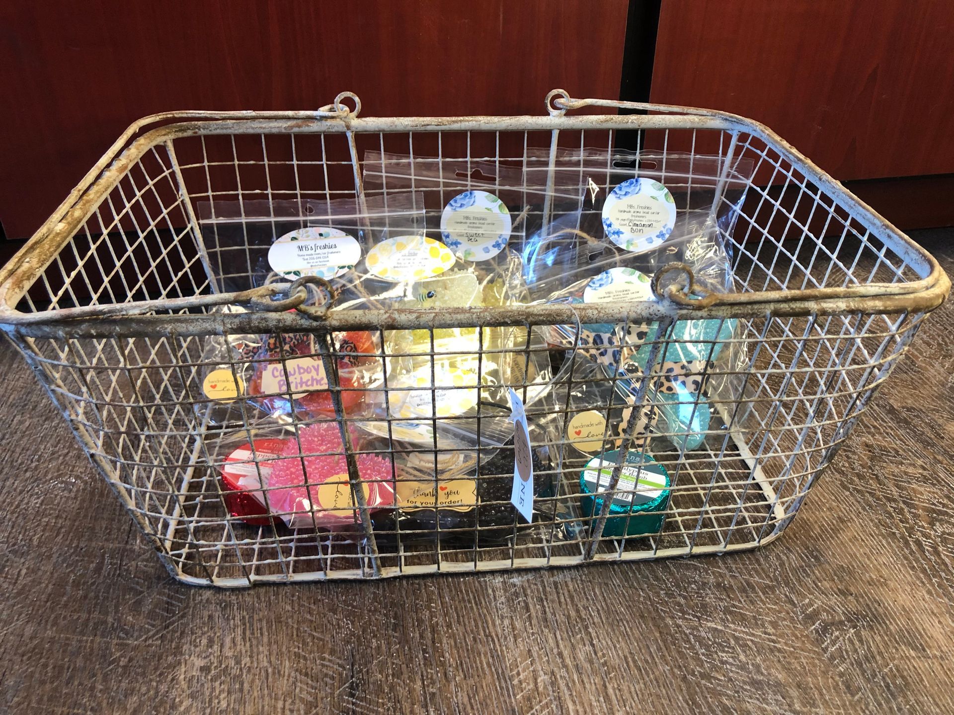 A wire basket filled with various items is sitting on a wooden floor.