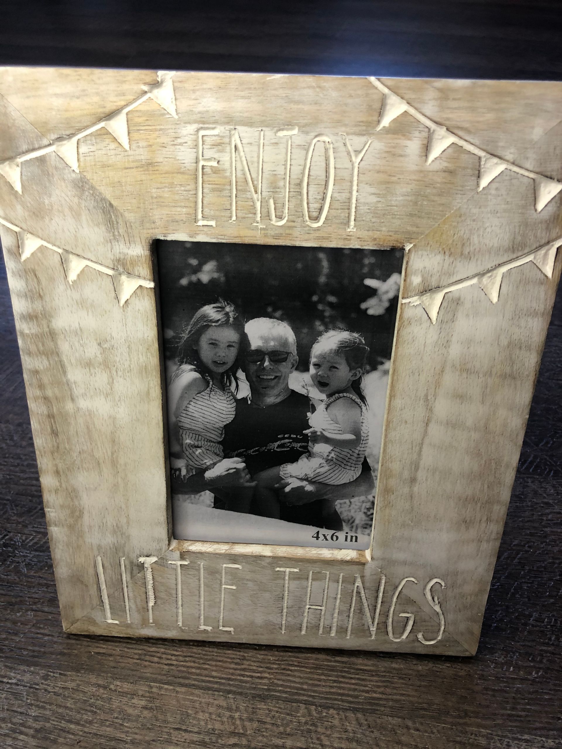 A picture frame with a picture of a family and the words `` enjoy little things '' written on it.