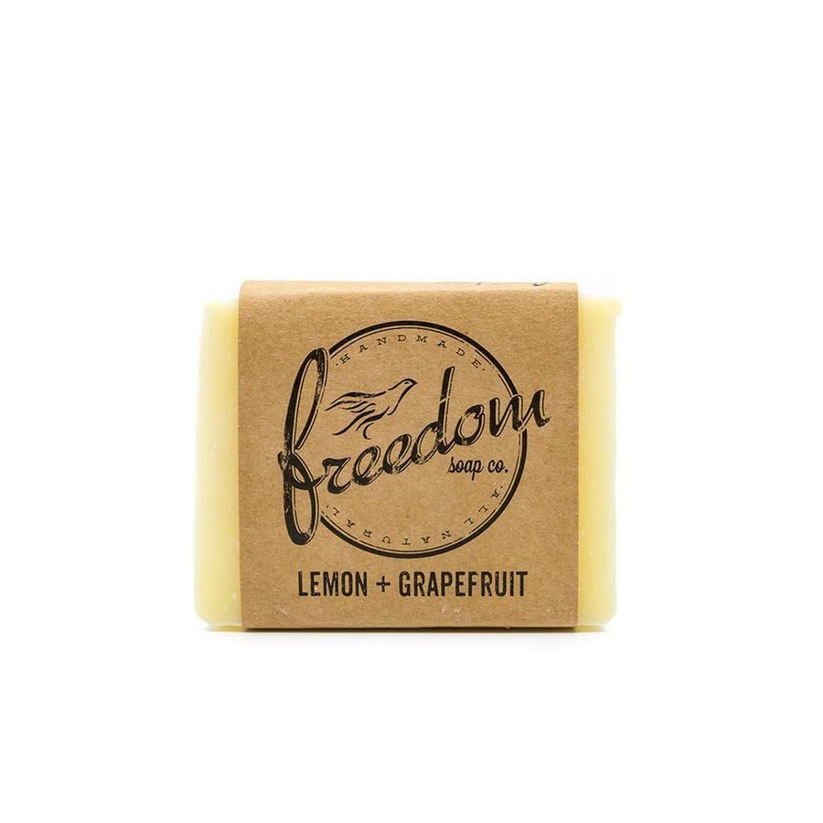 A bar of lemon and grapefruit soap is sitting on a white surface.