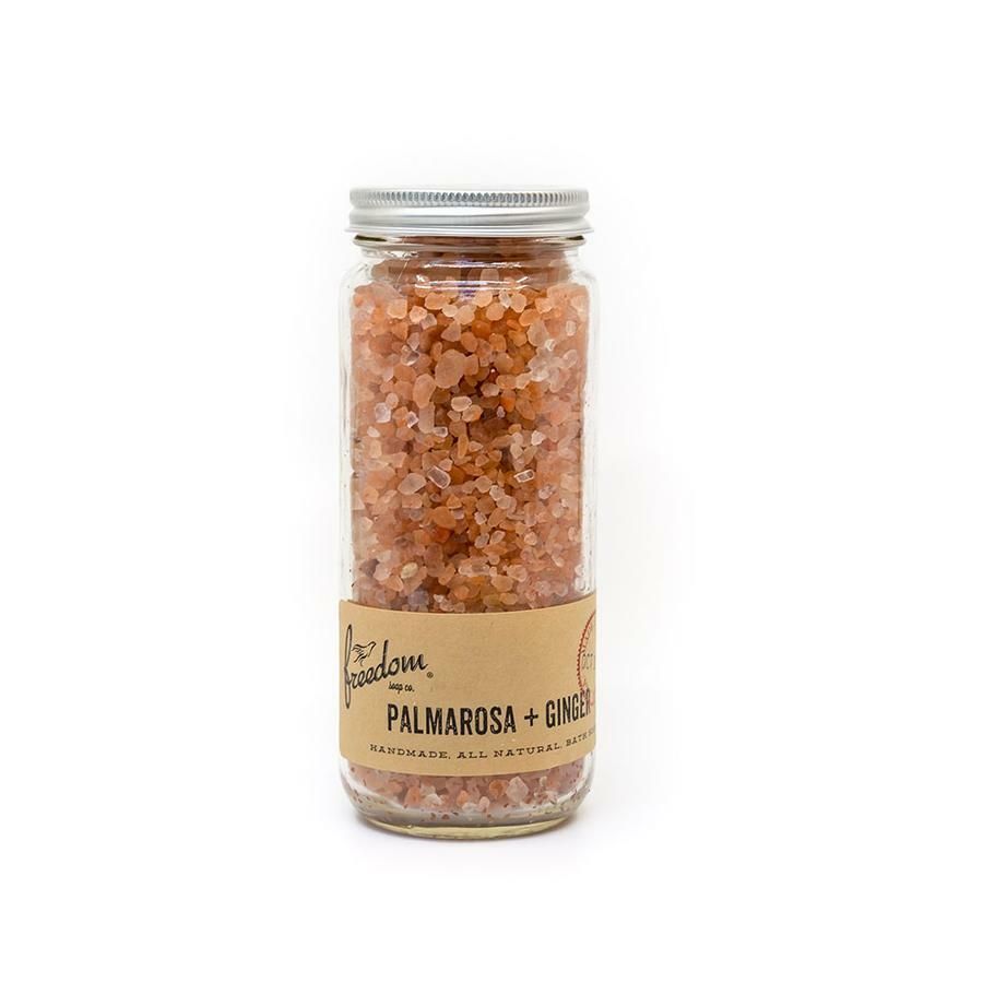 A glass jar filled with pink salt on a white background