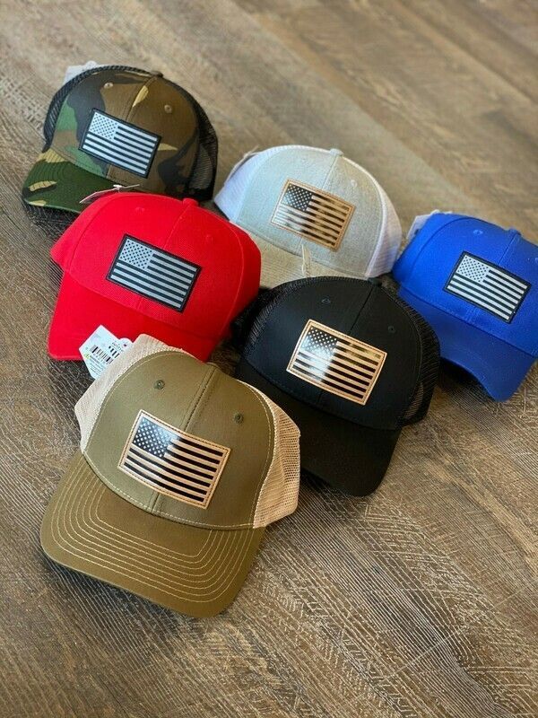 A group of hats with american flags on them are sitting on a wooden floor.