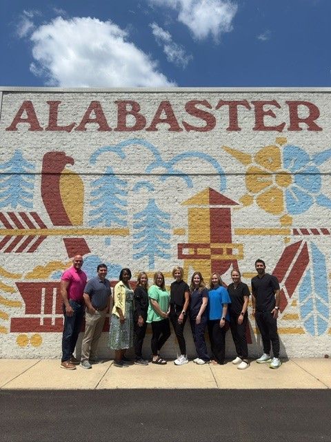 A group of people standing in front of a wall that says alabaster
