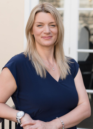 Kelly Owen stands facing the camera and smiling