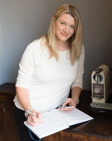Kelly Owen stands holding paper and reading 