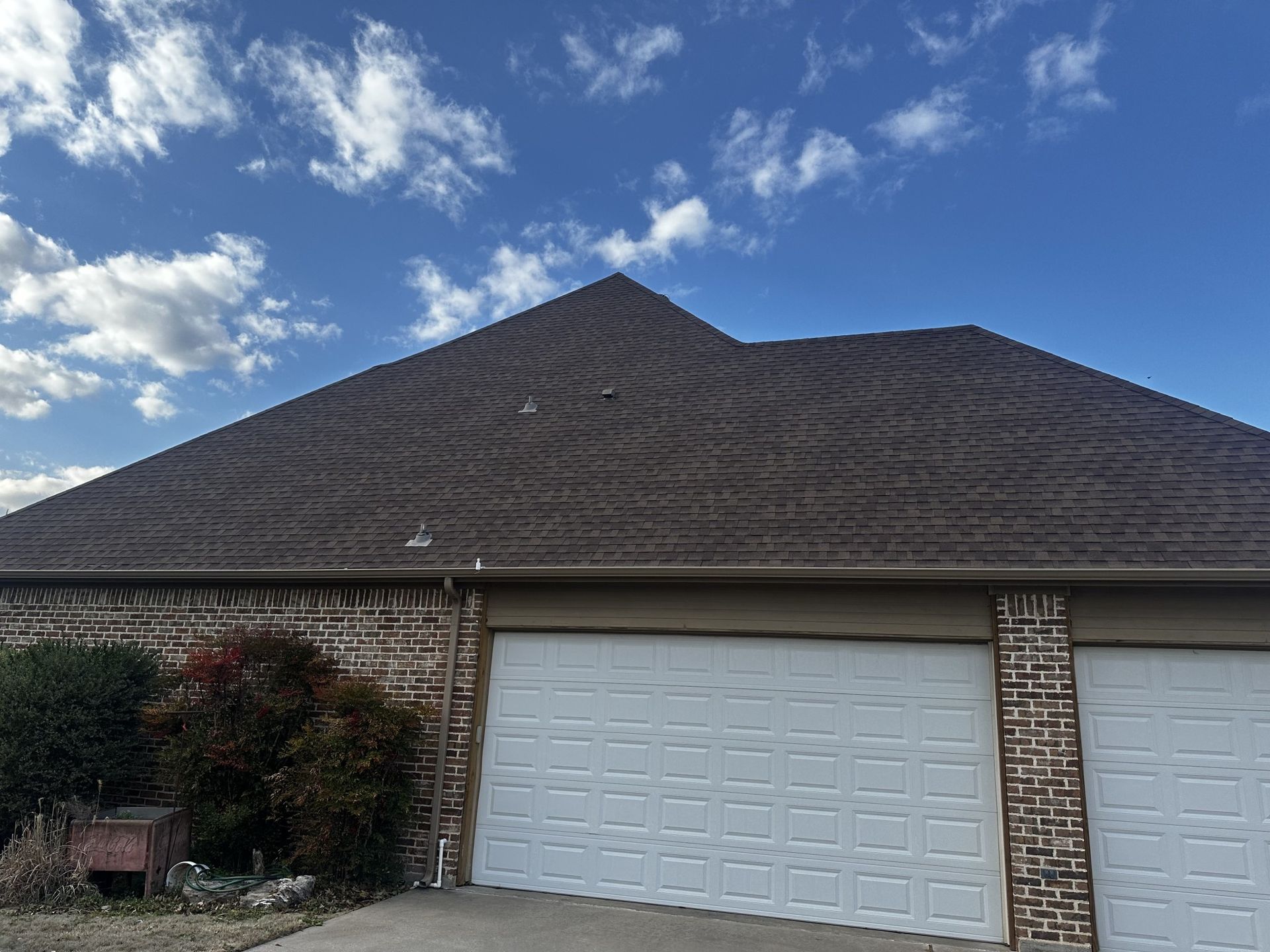 Brown roof with swirling patterns over a garage, blue sky with clouds.