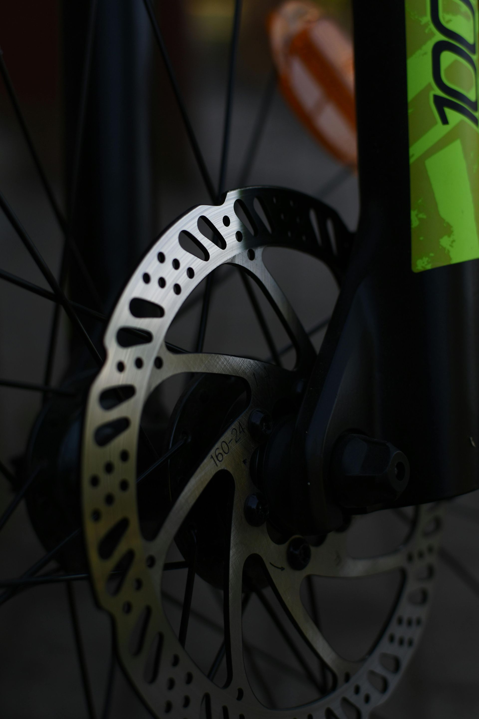 Close-up van een fietsschijfrem en -wiel met een neon groen frame.