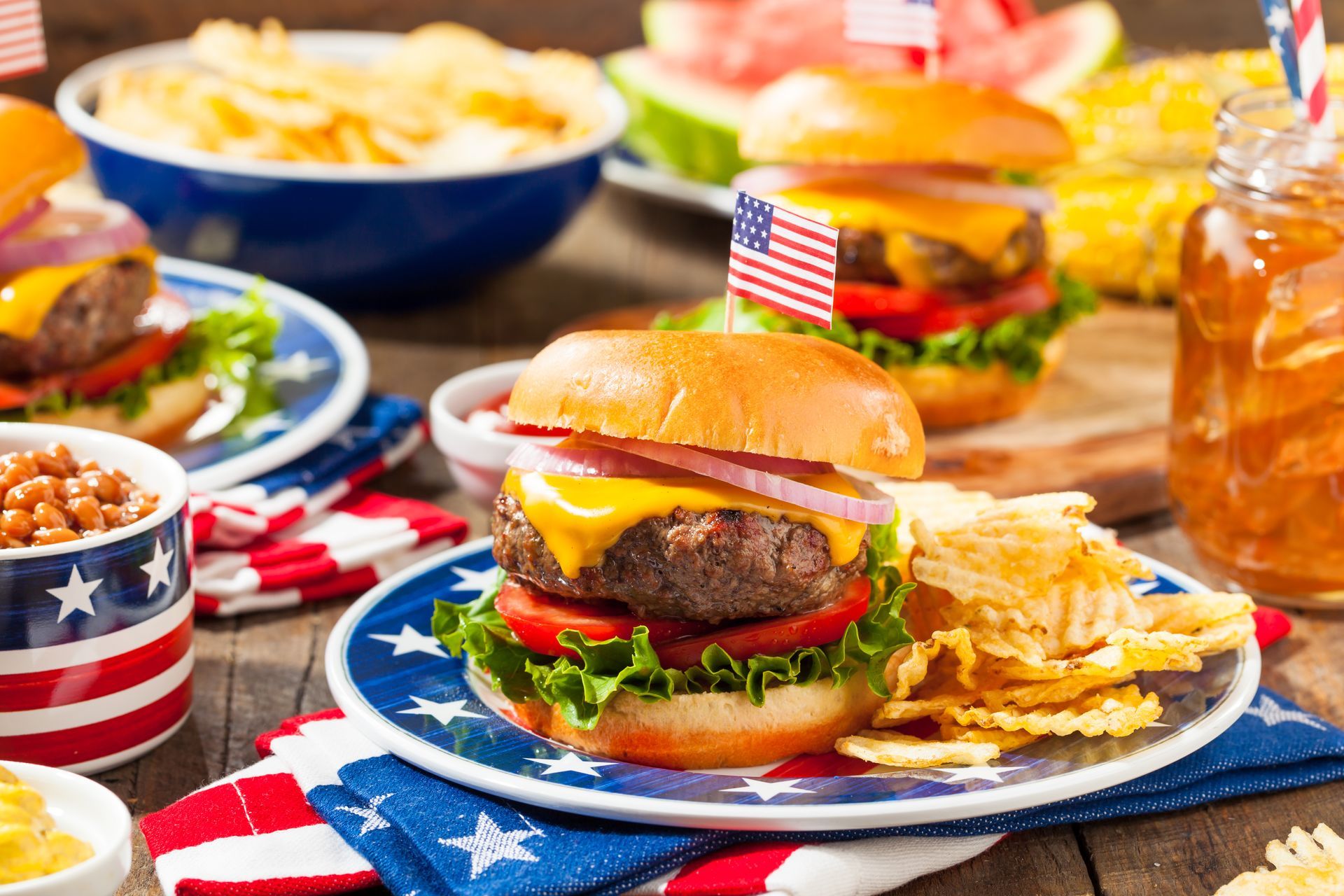 Patriotic cookout spread with burgers, fries, and American flags on red, white, and blue plates