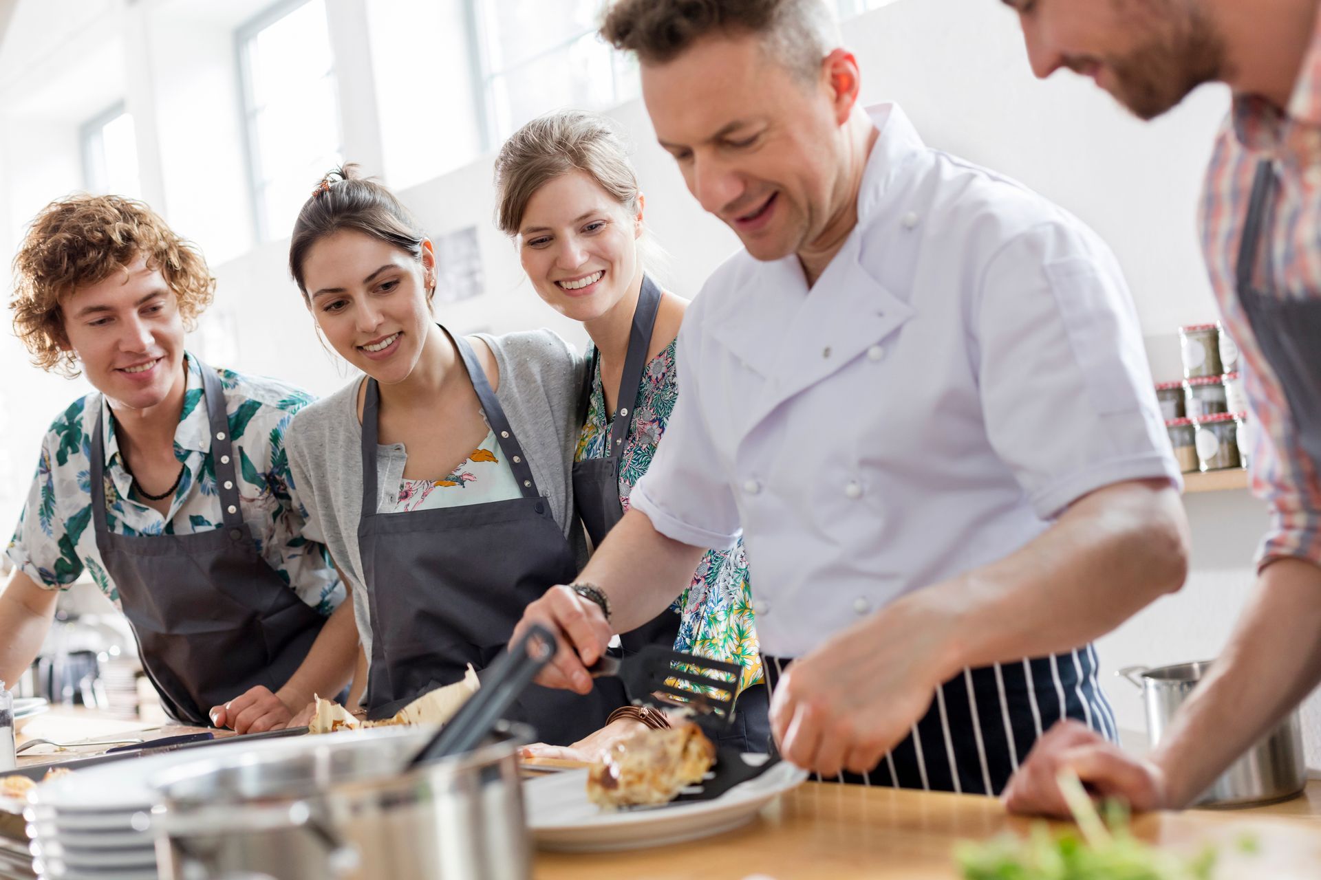 People cooking together in a bright kitchen, smiling and preparing food at a counter