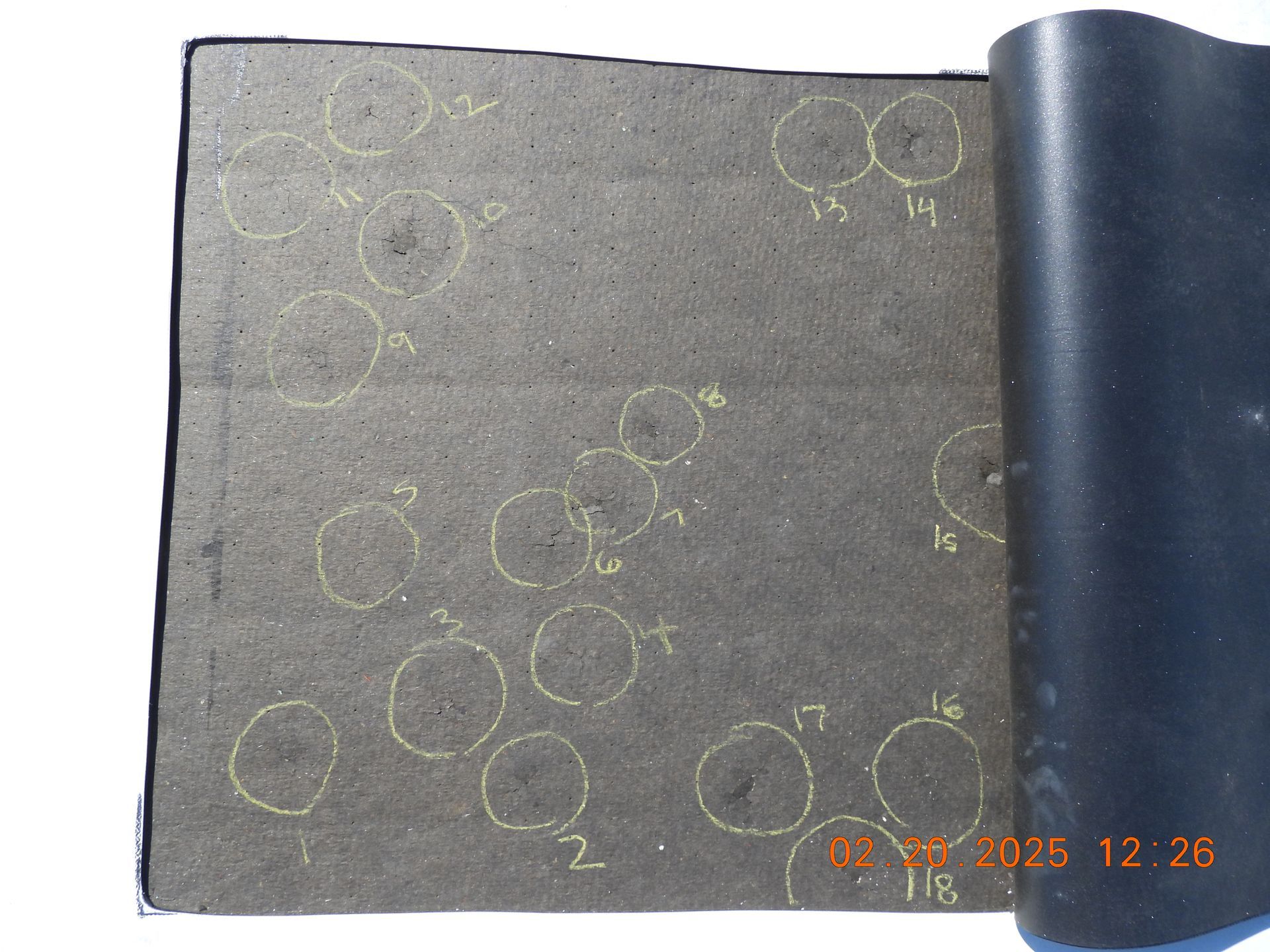 Dark gray fabric with faint yellow circular markings and a black folded edge in the upper right