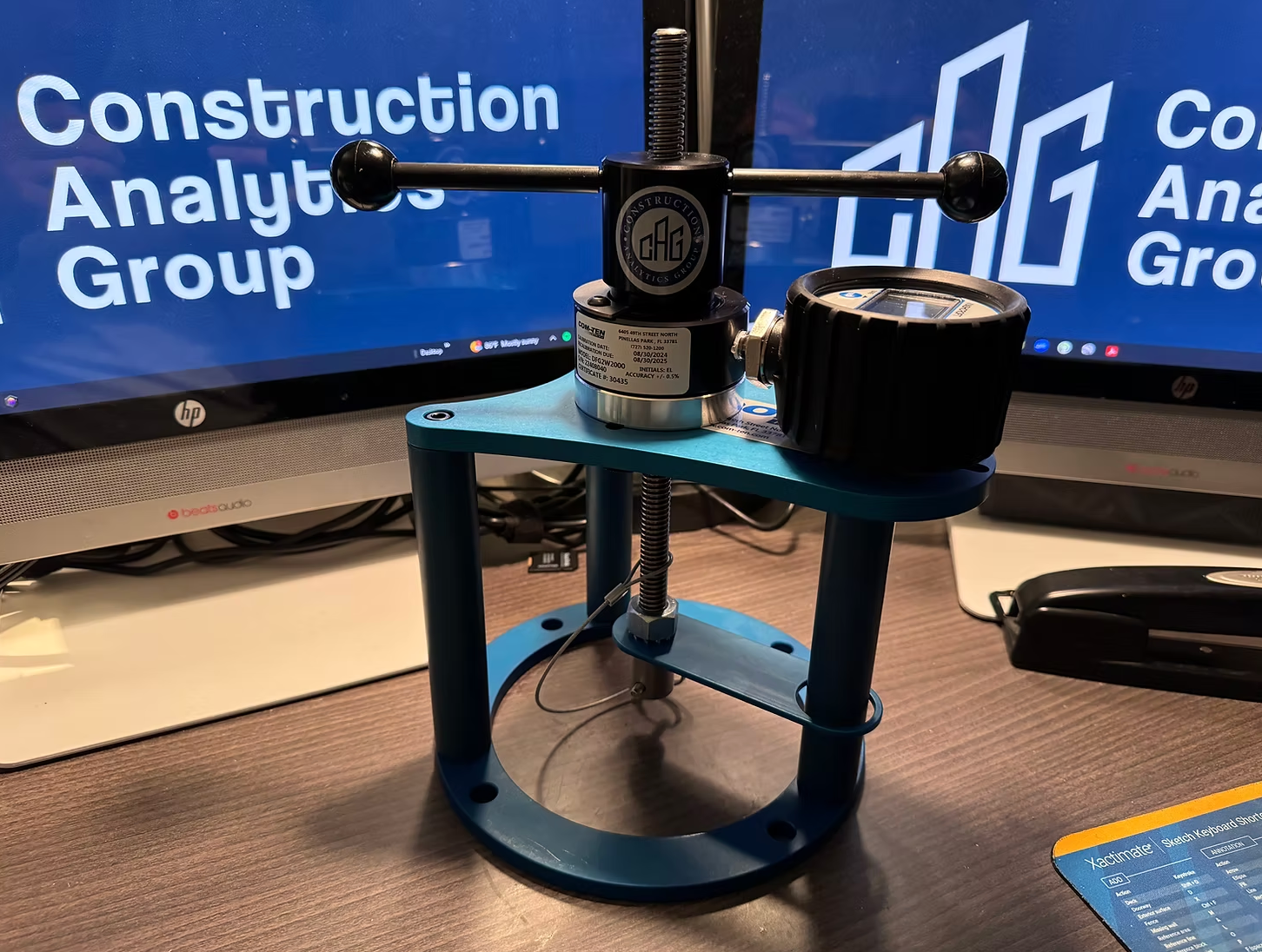 Blue drone on a desk in front of monitors showing “Construction Analytics Group” logos
