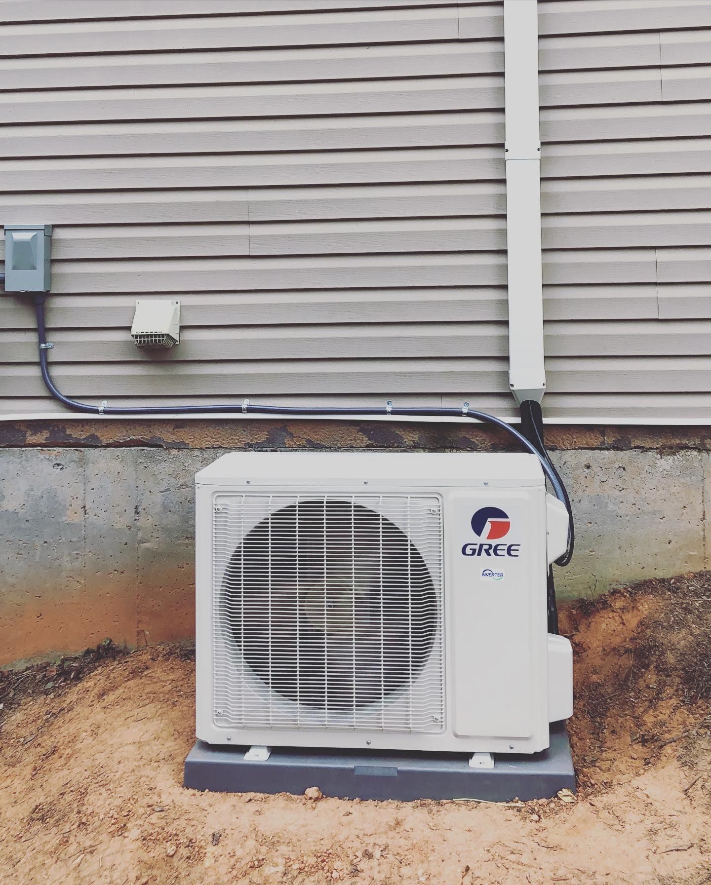A gree air conditioner is mounted on the side of a house