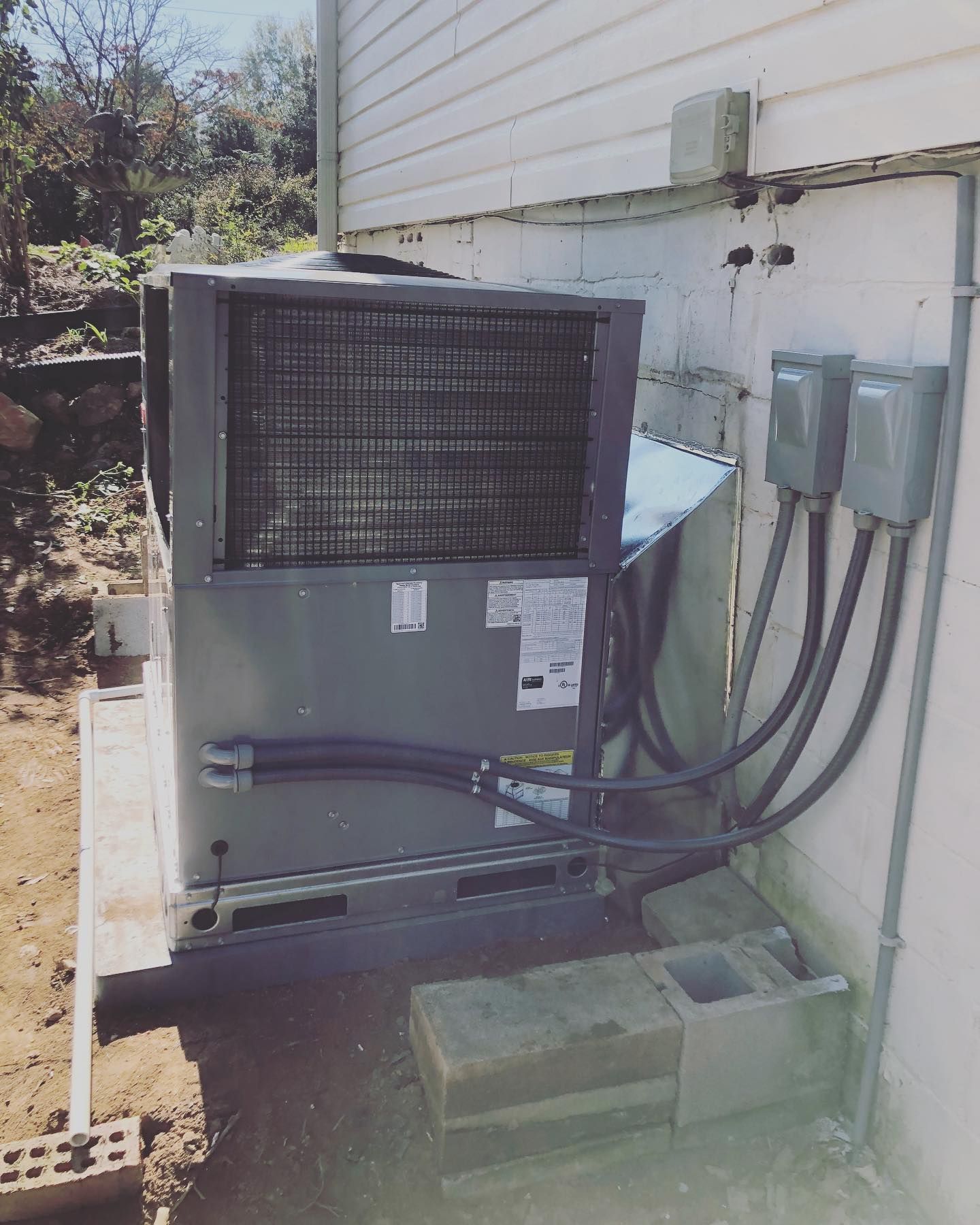 A large air conditioner is attached to the side of a house.