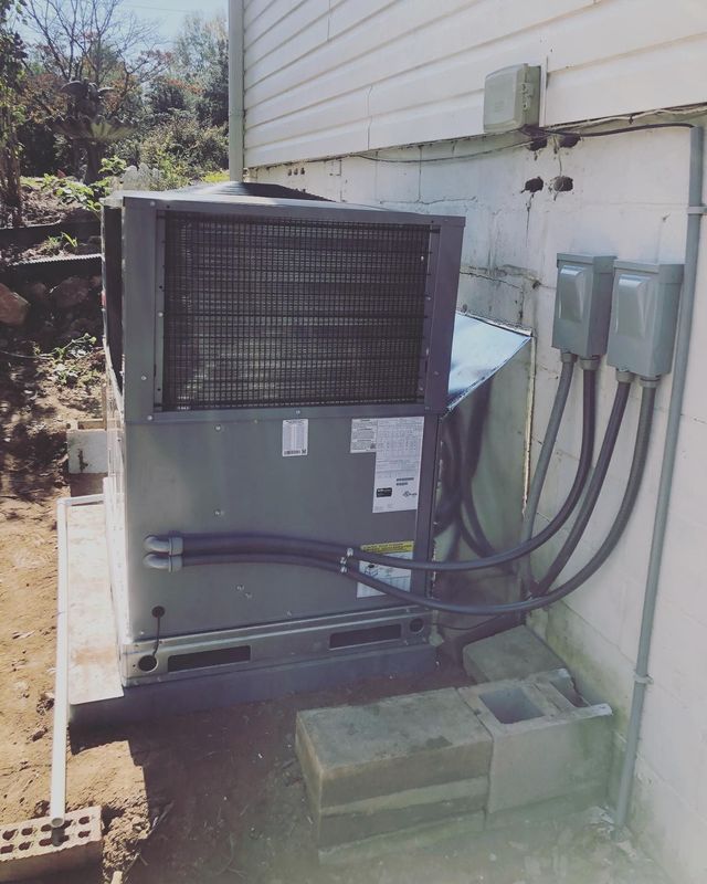 A large air conditioner is attached to the side of a house.