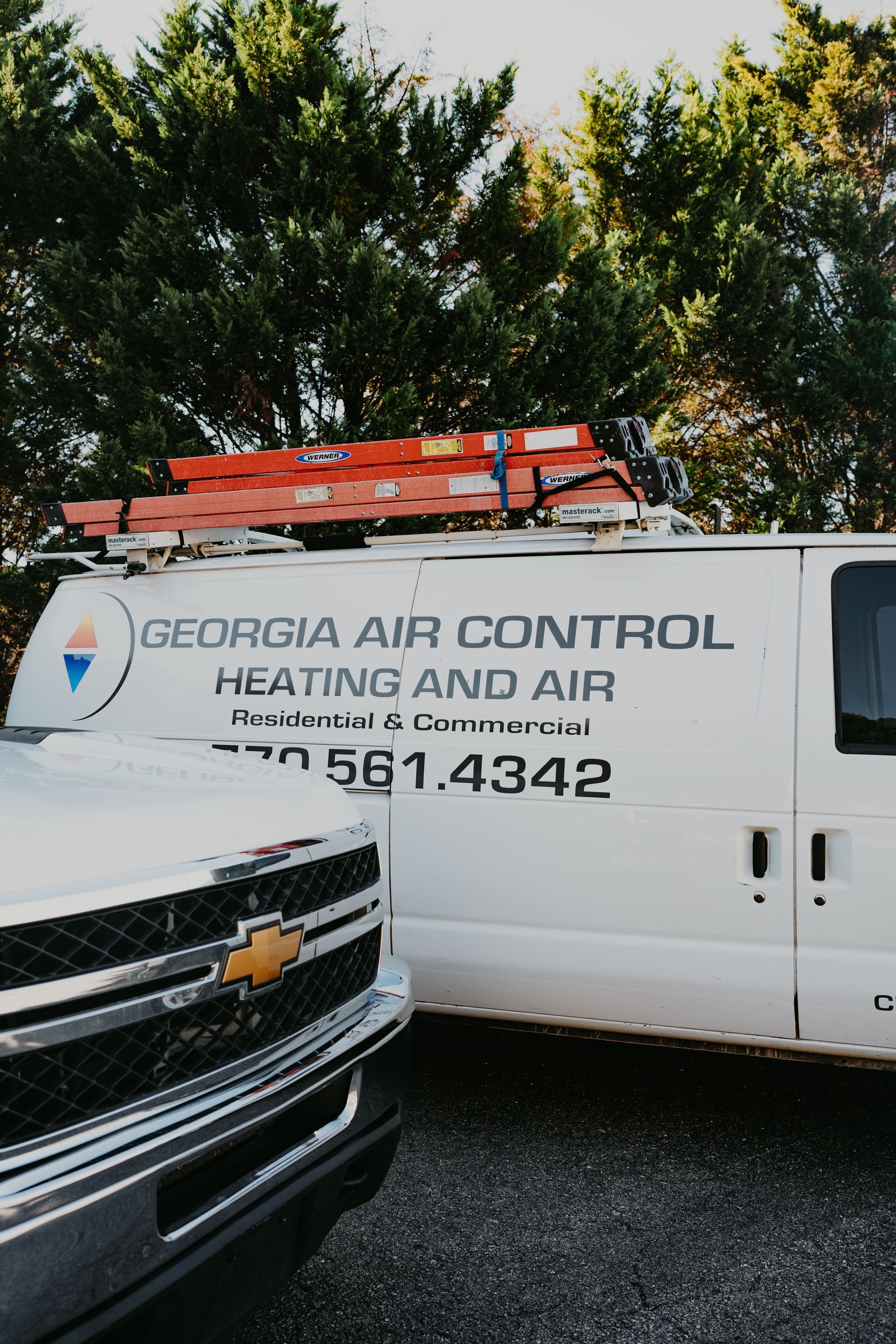 Two georgia air control heating and air vans are parked next to each other.